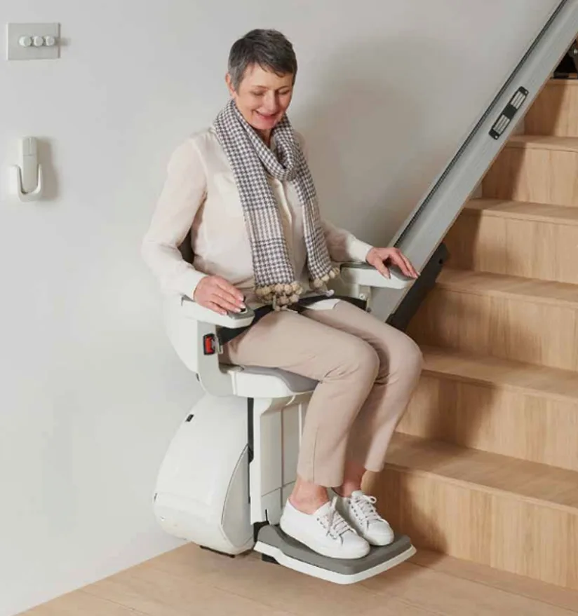 Image shows a lady using the Access HomeGlide stairlift