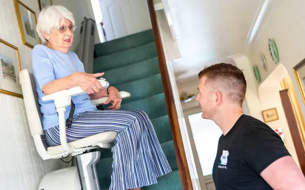 Image shows a lady on a stairlift talking to an EMS engineer