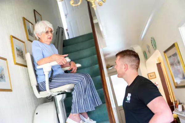 Image shows an EMS engineer talking to a lady using a stairlift in her home