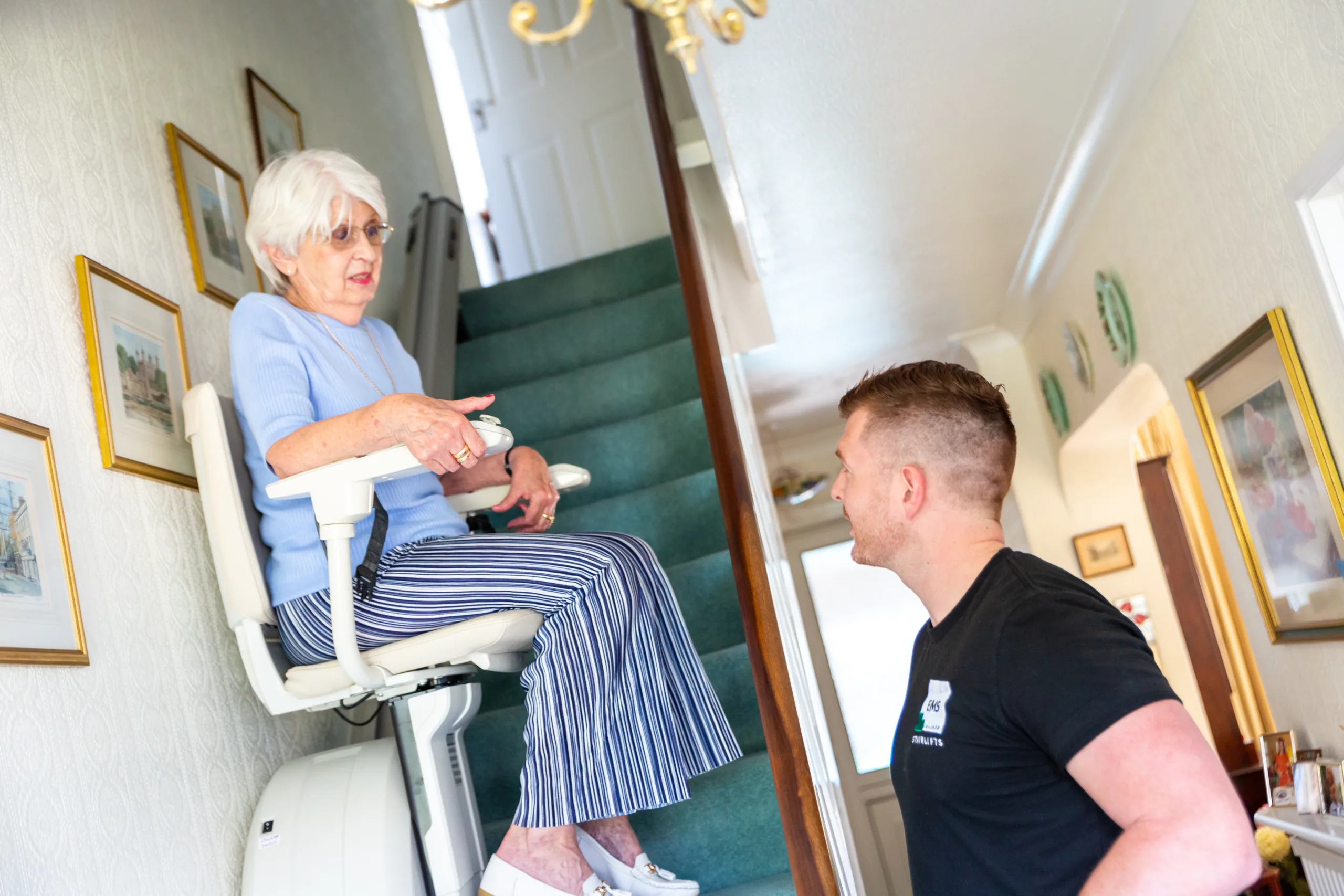 EMS-160 (4) Image shows an EMS engineer talking to a lady using a stairlift in her home