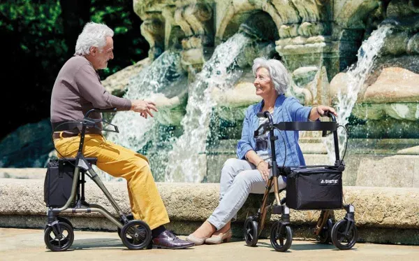 Image shows a man and a woman siting by a fountain. Both have walker mobility aids